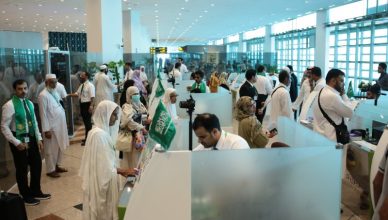 Pilgrims going to perform hajj to Saudi Arabia standing for visa check.